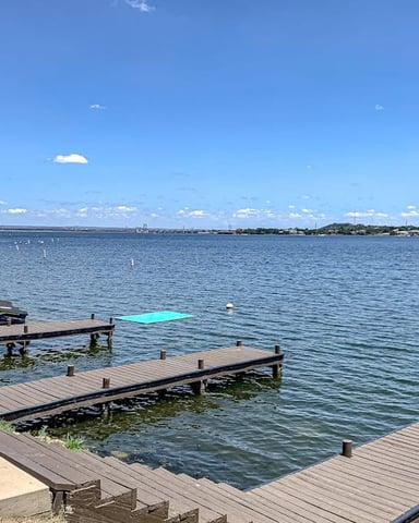 Waterfront property with wooden docks, moored boats, and bay view under clear blue sky