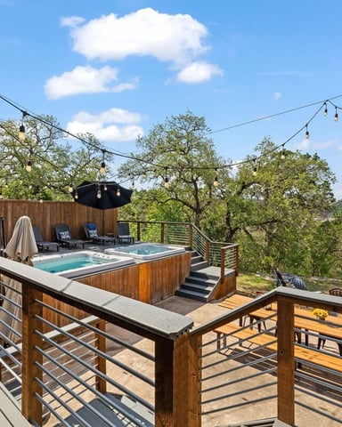 Backyard patio with four blue Adirondack chairs around fire pit, ranch house and green lawn beyond