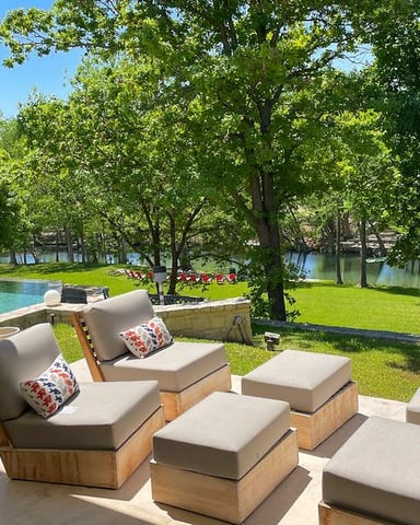 Backyard with illuminated pool, basketball hoop, cottage, lounge chairs, and string lights in trees at dusk
