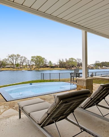 Waterfront property with wooden Adirondack chairs on lawn, boat dock and metal-frame boathouse on river