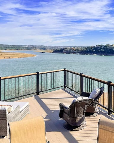 Waterfront lawn with Adirondack chairs around fire pit, boat dock, and river view with forested hills